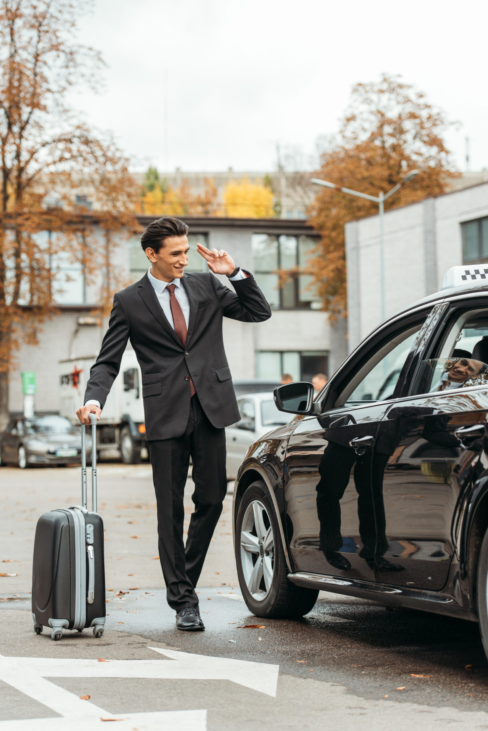 Businessman with suitcase smiling to taxi driver